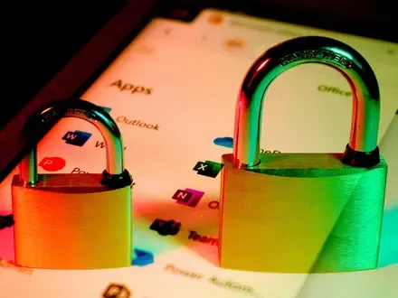 Two brass padlocks superimposed on a photo of a device screen showing the Microsoft 365 app launcher.