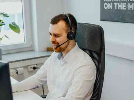 A man with a headset sitting in a chair behind a desk